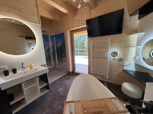 a bathroom with a tub and a sink and a tv at Wellness Chalet Zirbitz in Lavantegg