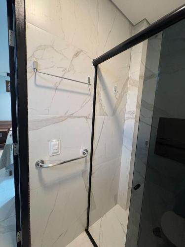 a shower with marble walls and a glass door at Pousada Caribdis in Paraipaba
