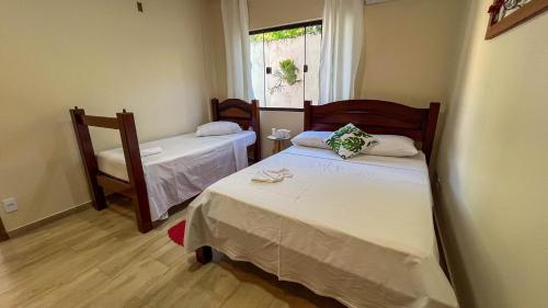 a small room with two beds and a window at Casa Amoreira Paraty in Paraty