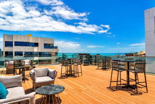 eine Terrasse mit Tischen und Stühlen auf dem Dach eines Gebäudes in der Unterkunft Intercity Maceio in Maceió