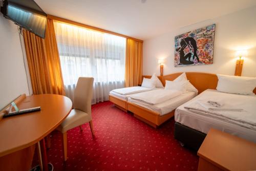 a hotel room with two beds and a table at Hotel Mondial Munich in Munich