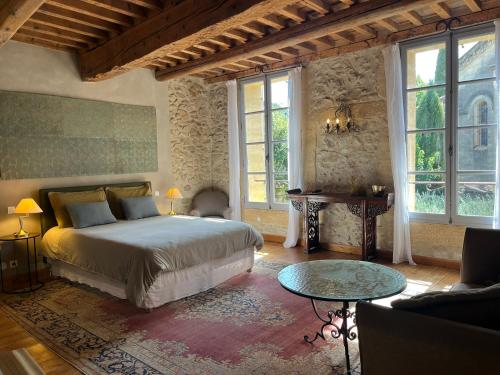 a bedroom with a bed and a table and windows at Le patio de Collias in Collias