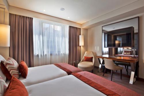 a hotel room with a bed and a desk at TURIM Marquês Hotel in Lisbon