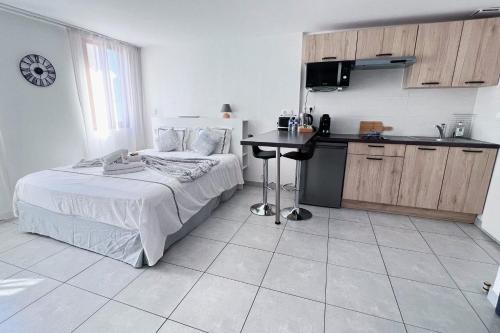 a bedroom with a bed and a table and a kitchen at Domus Via Domitia in Narbonne