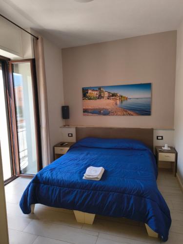 a bedroom with a blue bed and a large window at BrezzaMarina in Sapri