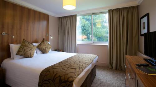 a hotel room with a large bed and a window at Aubrey Park Hotel in Hemel Hempstead