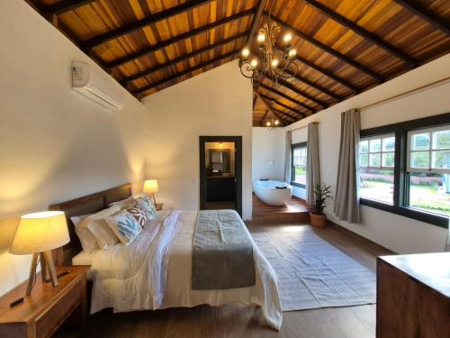 a bedroom with a bed and a bathroom with a tub at Pouso Antônio d'Maria in Tiradentes
