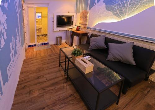 Una sala de estar con un sofá negro y una mesa. en Deer Moon Hostel, en Kenting