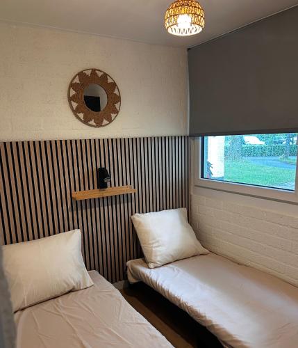 a room with two beds and a window and a mirror at Cosy 26 - Zuid-Limburg in Simpelveld