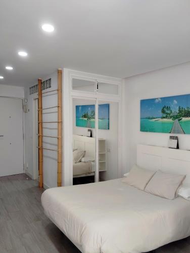 a white bedroom with a large bed and two windows at Hercules Suite in Benalmádena