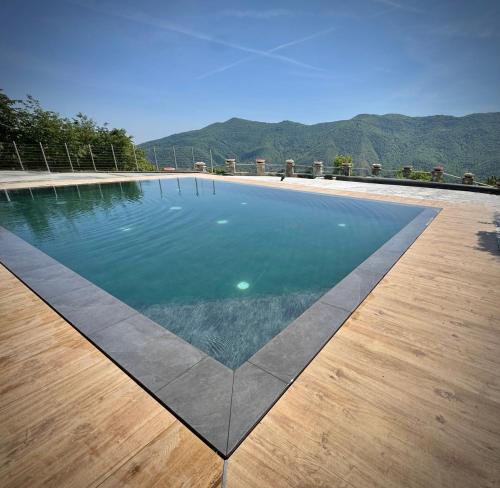 a swimming pool on a wooden floor with mountains in the background at B&B Bernacco in Vallio Terme