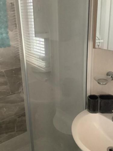 a white bathroom with a sink and a shower at Home from Home in Eyemouth