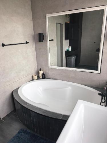 a bath tub in a bathroom with a large mirror at Protea House - self-catering house with a Pool in Durban