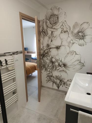 a bathroom with a drawing of flowers on the wall at La PETITE MAISON in Gourdan-Polignan