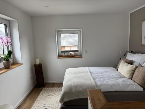 a white bedroom with a bed and a window at Fichtennest in Sundern