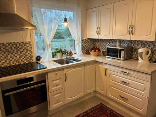 a kitchen with white cabinets and a sink and a window at Hus in Risskov