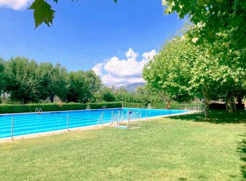 a large swimming pool in a yard with a grass field at Villa Lorelia in La Adrada