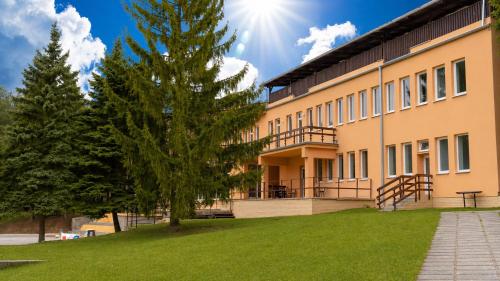 ein Gebäude mit einem Baum davor in der Unterkunft HLBOKÉ Hotel & Lesopark in Bojnice