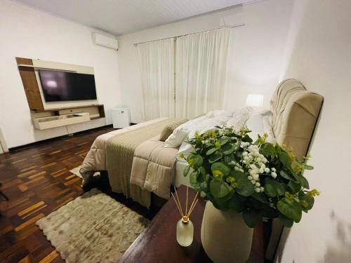 a bedroom with a bed and a tv and a couch at Hotel Pousada La Vierro in Ponta Grossa