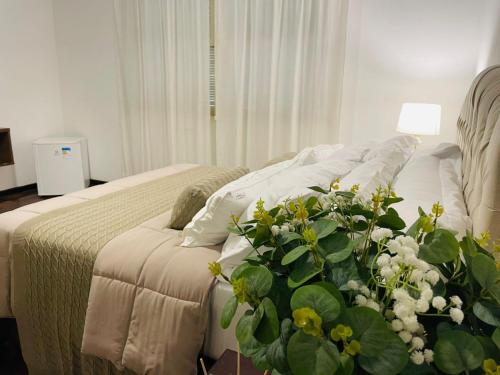 a bedroom with a bed with white pillows and a plant at Hotel Pousada La Vierro in Ponta Grossa
