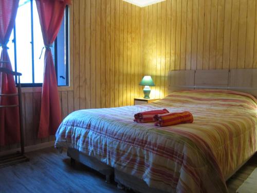 a bedroom with a bed with two red objects on it at Cabaña Pehuen in San José de Maipo