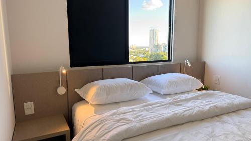 a bedroom with a bed with two pillows and a window at Apartamento Premium com 2 quartos in Palmas