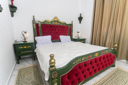 a bedroom with a large bed with a red headboard at Hotel Ksar Eljem in El Jem