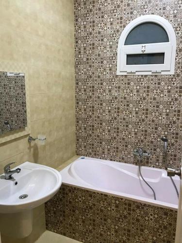 a bathroom with a tub and a sink and a window at Hotel Ksar Eljem in El Jem