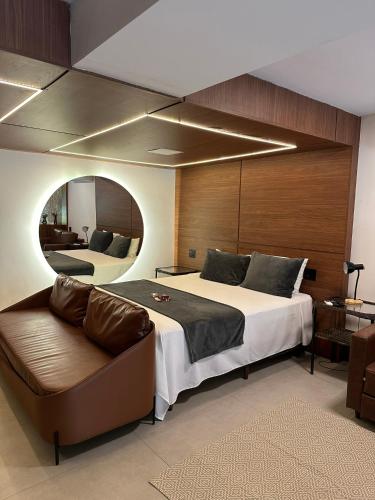 a bedroom with a bed and a couch and a mirror at Gaia Hotelaria in Teresópolis