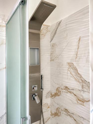 a shower in a bathroom with a marble wall at Infinity Blue in Cefalù