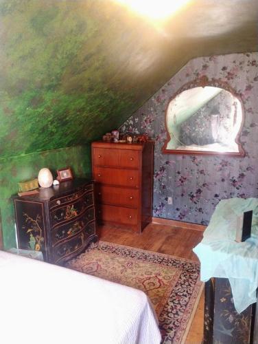 a bedroom with a bed and a dresser and a painting at Magical stone cottage in Pine Grove Mills