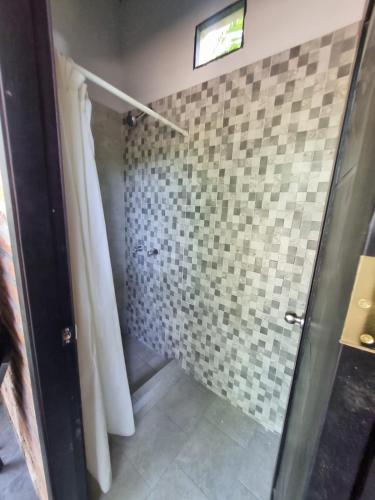 a bathroom with a shower with a tile wall at Rio Olón ecolodge in Olón