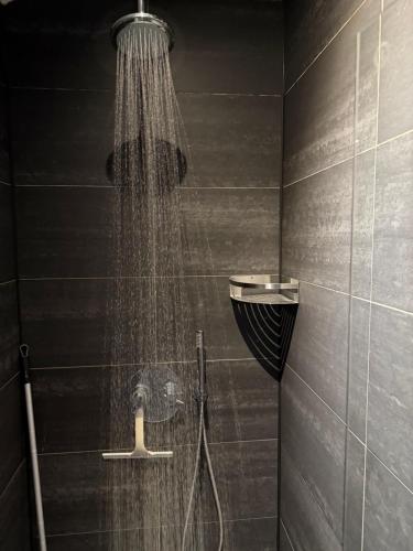 a shower in a black bathroom with a shower at Amsterdam Countryside met Airco ,Geweldig uitzicht, luxe keuken,wasmachine,droger,gratis fietsen in Den Ilp