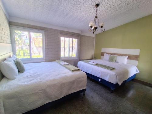 a bedroom with two beds and a chandelier at Hotel Urban Home in Guatemala