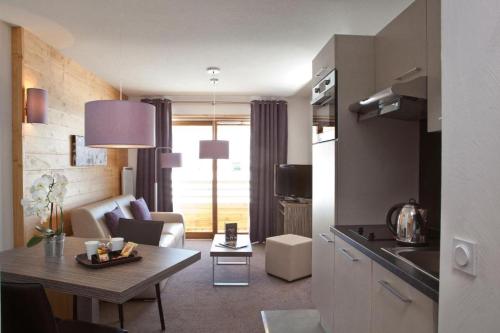 a kitchen and living room with a table and a couch at Alpenrose Alpe d'Huez in LʼHuez