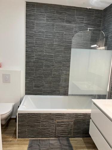 a bathroom with a bath tub and a toilet at Cosy uccle chic flat in Brussels