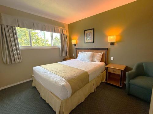 a hotel room with a bed and a chair at Diplomat Motel in Nanaimo