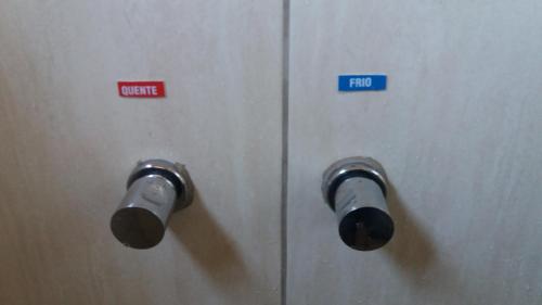 a metal door with two knobs and a sign on it at Pousada Flores em Vida in Olímpia