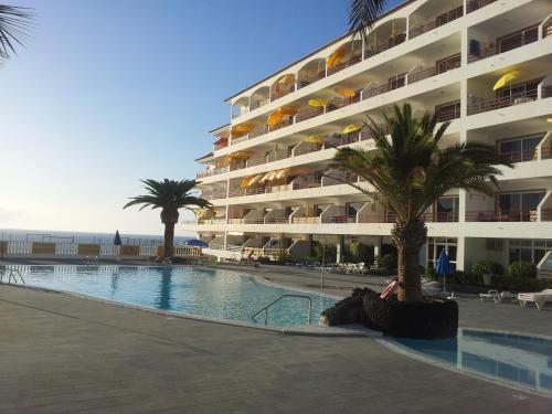 プエルト・デ・サンティアゴにあるLa Arena Beachのヤシの木とスイミングプールのある大きなアパートメントです。