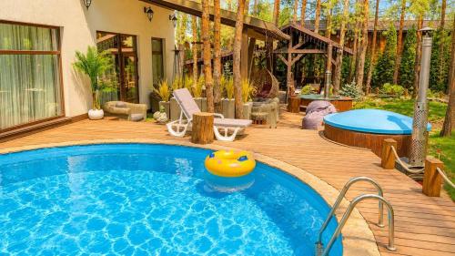 a swimming pool on a wooden deck next to a house at Дом в лесу 1dom club in Protsev