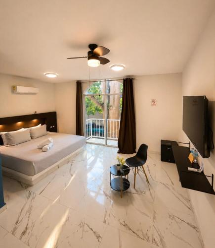 a bedroom with a bed and a television and a table at Hotel YA'AX HA' Bacalar in Bacalar