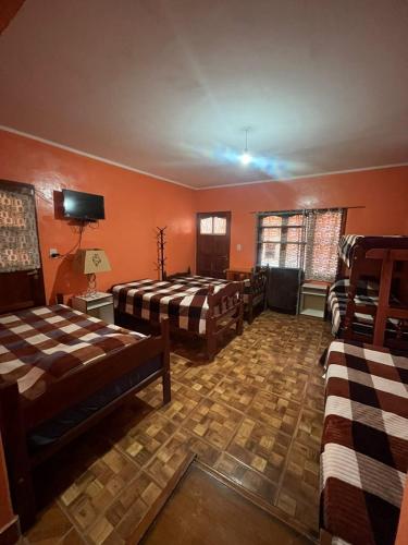 a room with three beds in a room with orange walls at HOSTAL LUCERO in Humahuaca