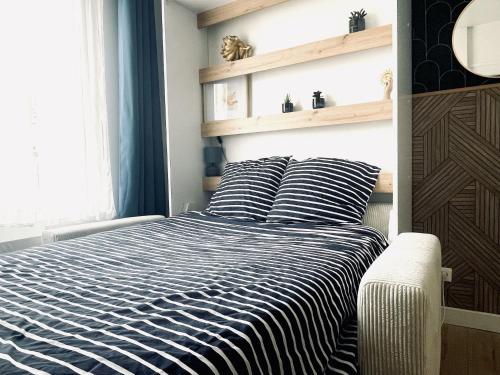 a bed with a black and white striped comforter in a bedroom at Croix rouge in Châtellerault