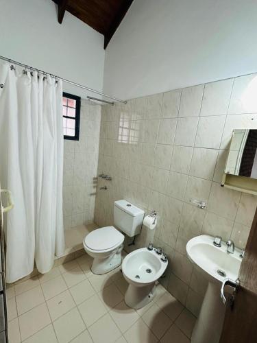 a white bathroom with a toilet and a sink at Solymar Alojamiento in Puerto Madryn