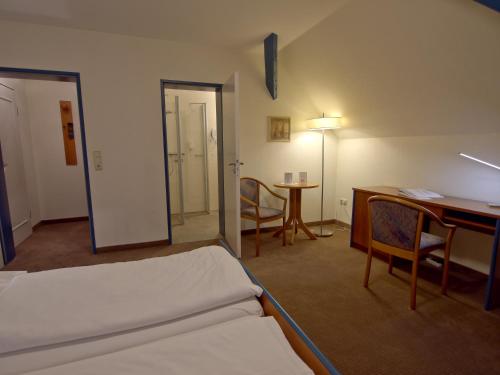 a room with a bed and a desk and a table at Hotel Friesische Wehde in Bockhorn