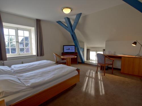 ein Hotelzimmer mit einem Bett, einem Schreibtisch und einem Tisch in der Unterkunft Hotel Friesische Wehde in Bockhorn