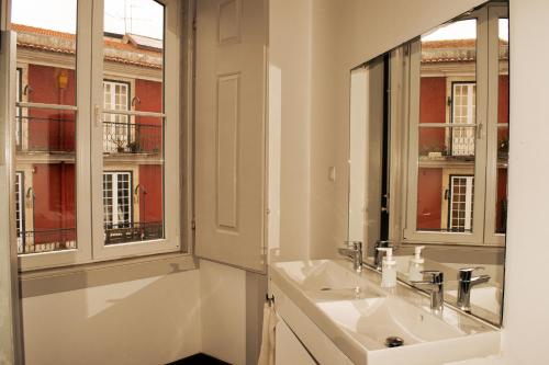 a bathroom with a sink and two windows at Inn Possible Lisbon Hostel in Lisbon