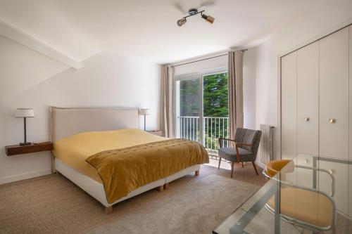 a bedroom with a bed and a chair and a window at Villa 96 Golf de la Baule avec piscine et spa in Saint-André-des-Eaux