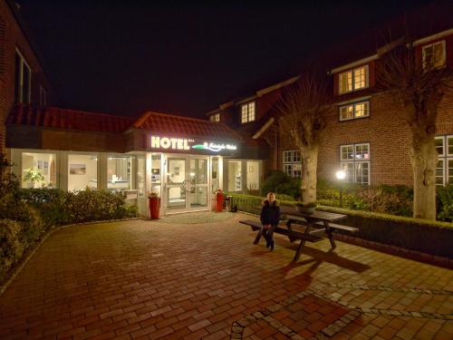 a woman sitting on a bench in front of a hotel at Hotel Friesische Wehde in Bockhorn