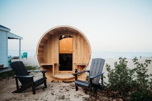 two chairs sitting in front of a circular building on the beach at Lake Huron Cottage 6 - 3 Bed 1 Bath in Lincoln Junction